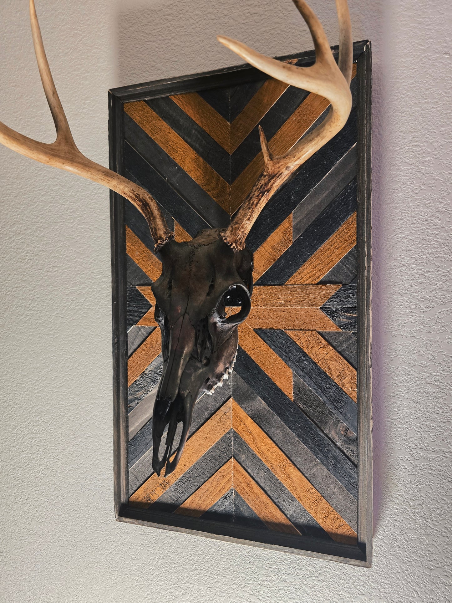 Decorative wall art with deer skull and antlers on a chevron-patterned background
