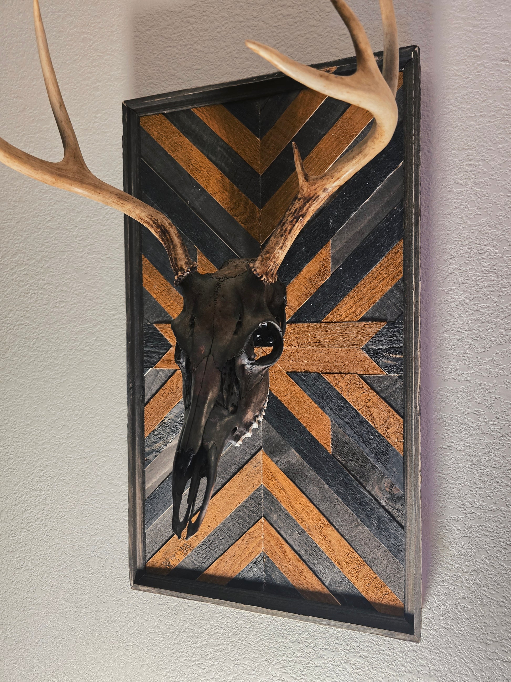 Decorative wall art with deer skull and antlers on a chevron-patterned background