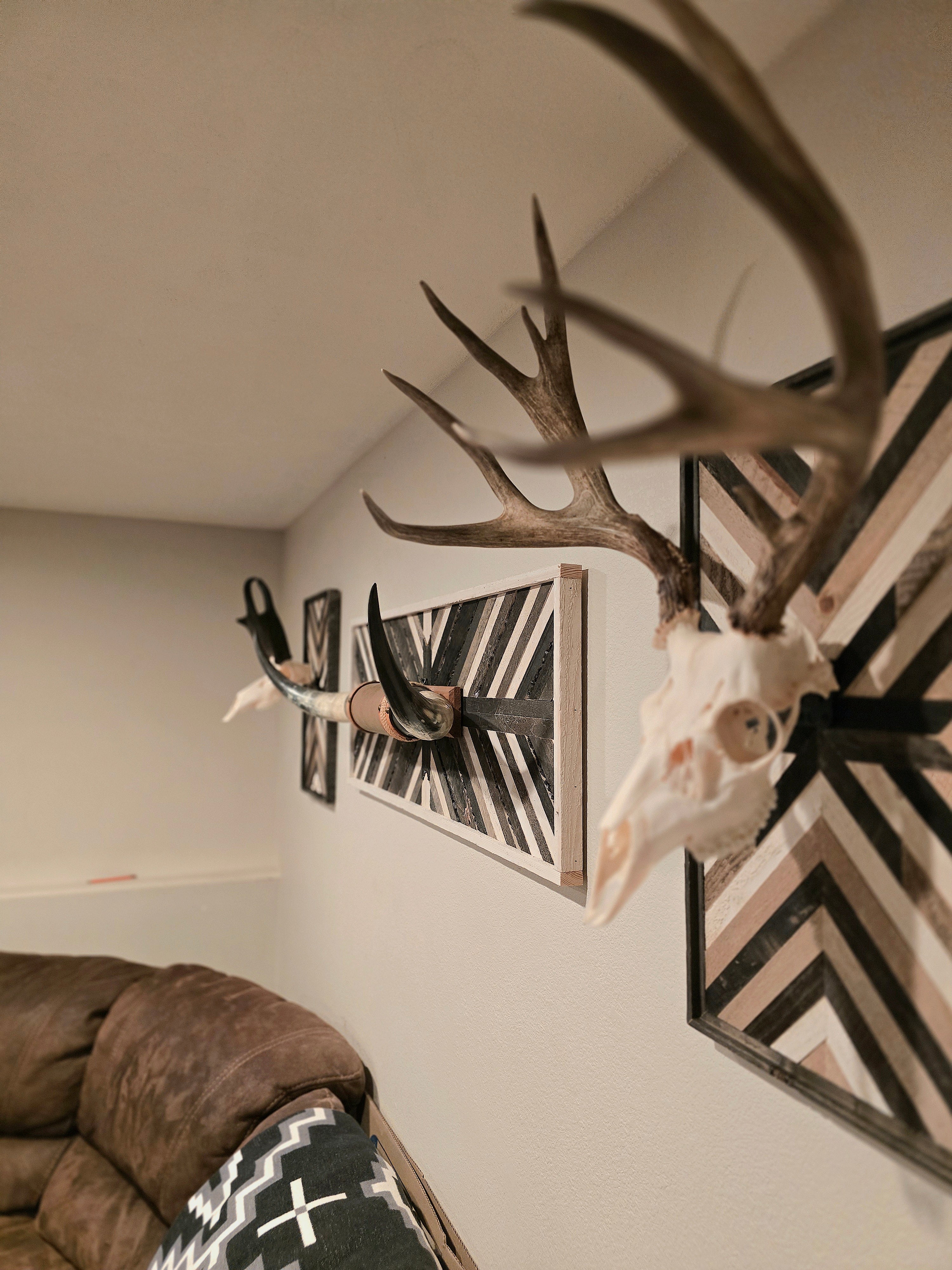 Decorative wall with mounted deer antlers,deer skulls and longhorns framed by geometric patterns.