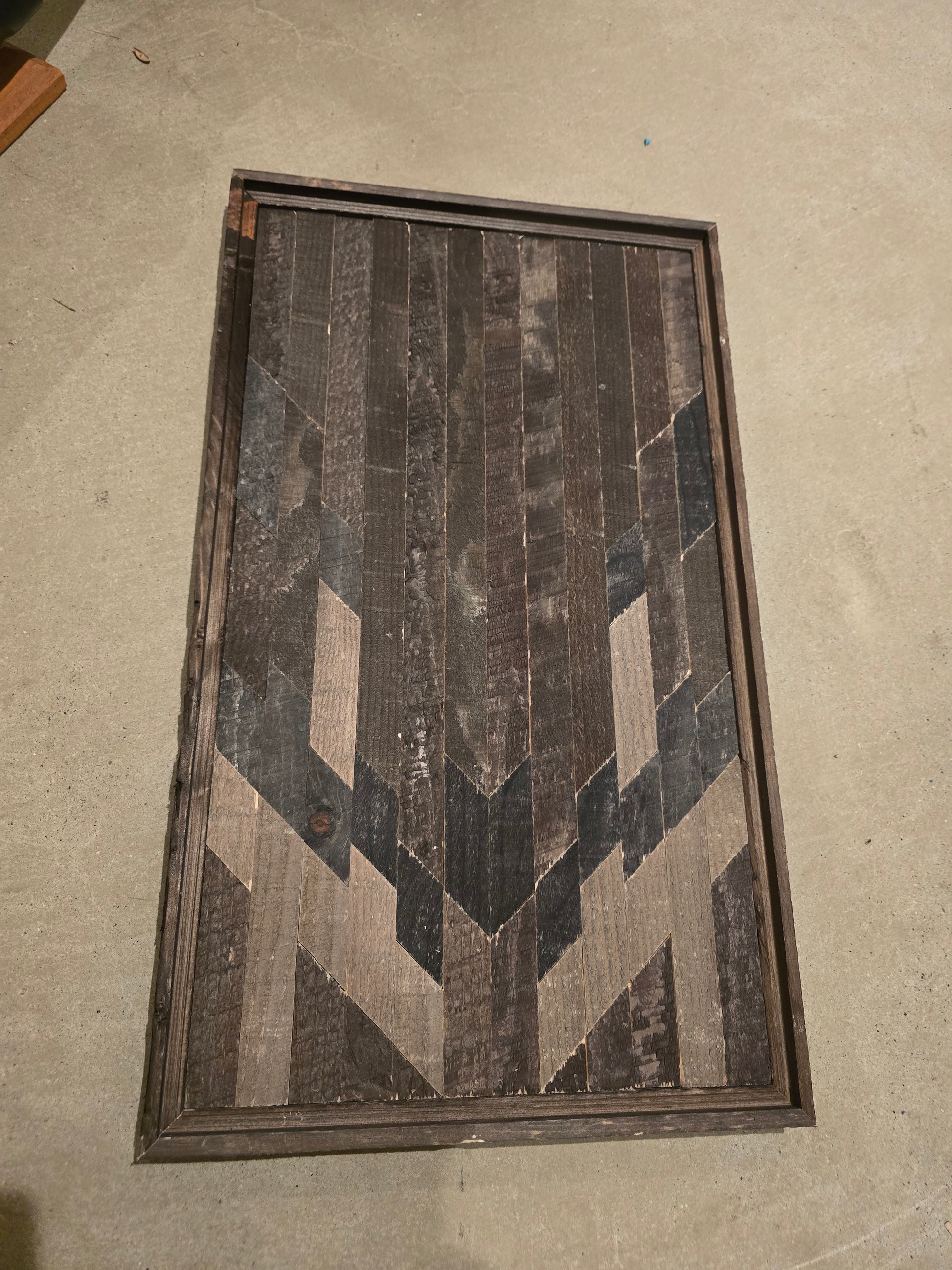 wood geometric pattern plaque on a concrete floor