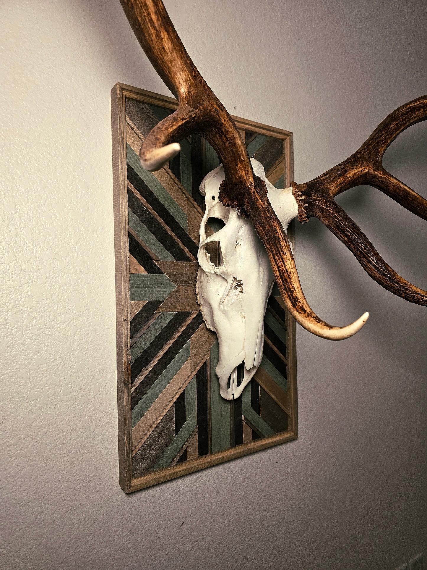 Decorative wall art with elk skull and antlers on a geometric-patterned background