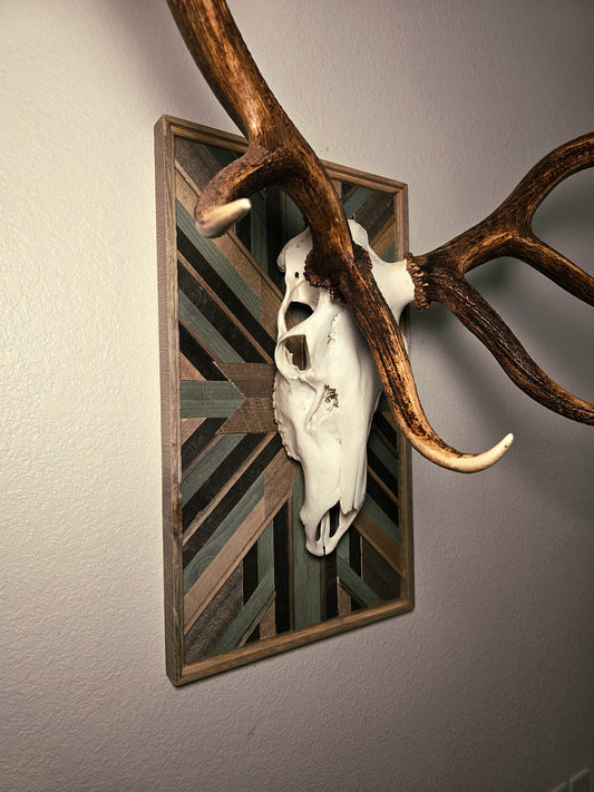 Decorative wall art with elk skull and antlers on a geometric-patterned background